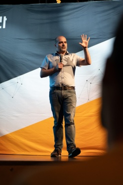 Ein Speaker mit Mikrofon hält eine Hand hoch